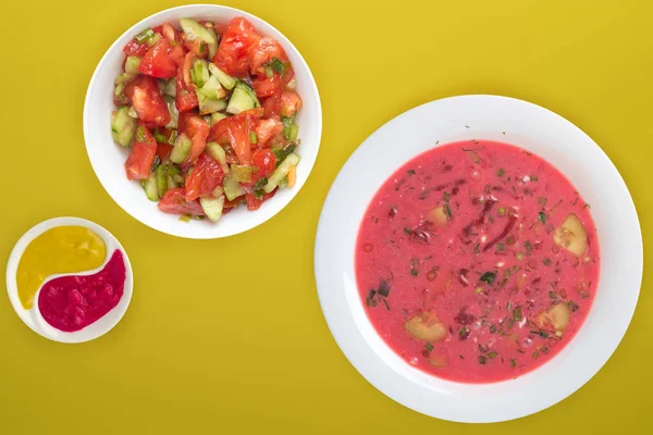 Beetroot soup a white plate with vegetable salad on a colored background. Vegetarian lunch. — 스톡 사진