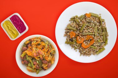 Sarımsaklı yeşil fasulyeli karabuğday ve renkli arkaplanda sebze salatası olan havuç tabağı. Beyaz tabakta diyet kahvaltısı.