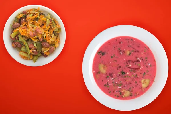 Beetroot soup a white plate with vegetable salad on a colored background. Vegetarian lunch. — 스톡 사진