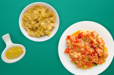 Renkli arka planda beyaz bir tabakta soğanlı haşlanmış domates. Soğan manzaralı haşlanmış domates. vejetaryen yemeği.