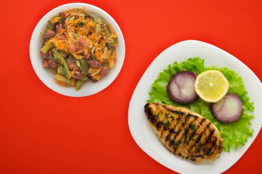 Sebzeli ızgara tavuk, limon, salata, renkli arkaplanda soğan..