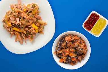 Berlin salatası beyaz bir tabakta, krlorlu bir arka planda. Sosis, salatalık, biber soslu salata. .