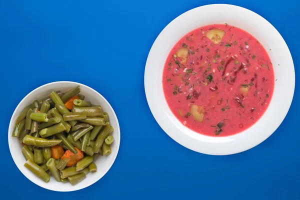 Beetroot soup a white plate with vegetable salad on a colored background. Vegetarian lunch. — 스톡 사진