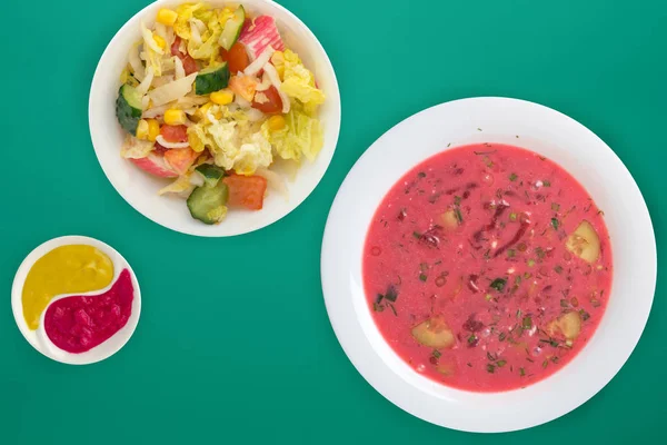 Beetroot soup a white plate with vegetable salad on a colored ba — 스톡 사진