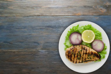 Ahşap arka planda sebzeli ızgara tavuk filetosu. Tavuklu fileto tabakta ızgara.