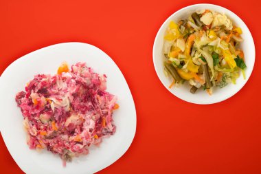 Beyaz bir tabakta kürk manto altında ringa balığı. Renkli bir arkaplanda kürkün altında ringa balığı. Ringa, pancar, havuç, mayonez ve soğan salatası. .