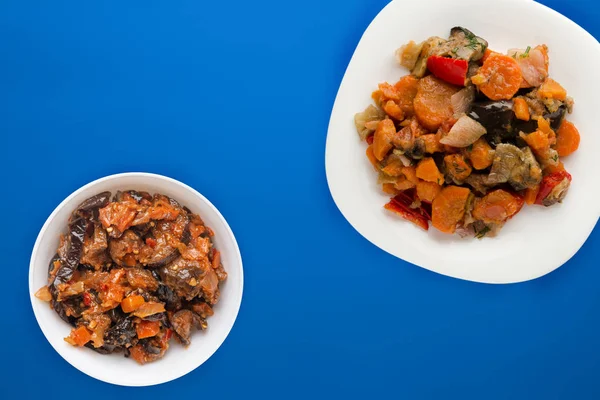 Рагу из овощей на белой тарелке. тушеные овощи на цветном фоне. вегетарианская еда — стоковое фото
