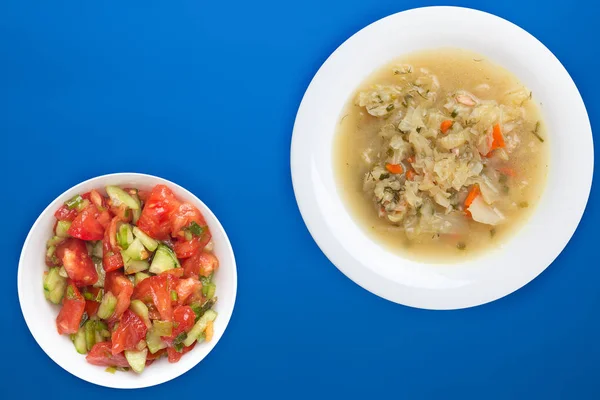 Cabbage soup on a white plate on a colored background. soup with vegetable salad. Vegetarian soup. — 스톡 사진