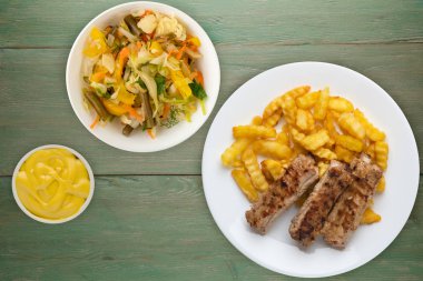 Beyaz tabakta domuz pirzolası ve patates, sebze salatası ve ahşap arka planda sos. Fast food 'un en iyi manzarası. Sağlıksız yiyecekler.