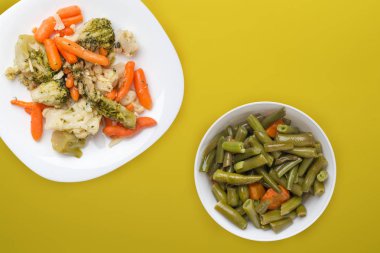  Beyaz tabakta Provencal sebzeler. Tabakta kızarmış sebzeler, sarı bir arka plan. Vejetaryen yemeği. Sağlıklı yiyecek manzaralı.