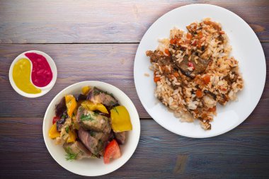 Kabaklı pilav, domatesli ve biberli beyaz tabakta. Sebzeli pirinç ve mor ahşap arka plan. Sağlıklı vejetaryen yemeği. Asya mutfağı üst görünümü