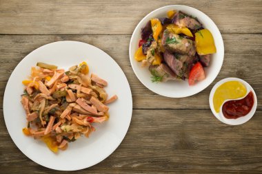 Berlin salatası ahşap bir arka planda beyaz bir tabakta. Sosis, salatalık, biber soslu salata. .