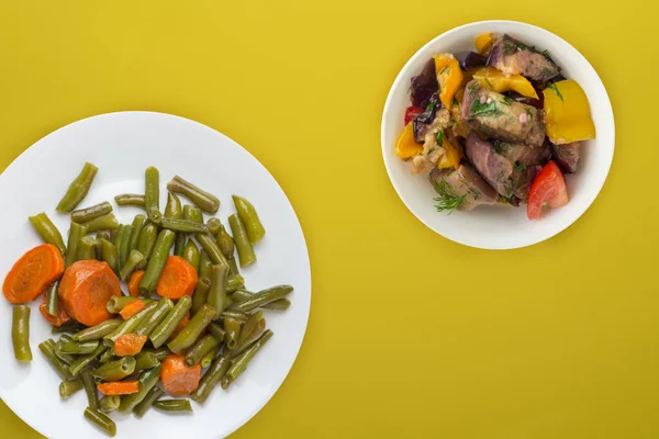 Green beans with garlic carrots on a white plate on a yellow background. green beans with carrots with vegetable vegetarian salad and sauce top view. healthy vegetarian food.flat lay