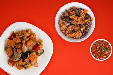 Beyaz tabakta sebze güveci. Kırmızı arka planda haşlanmış sebzeler. Vejetaryen yemekleri.