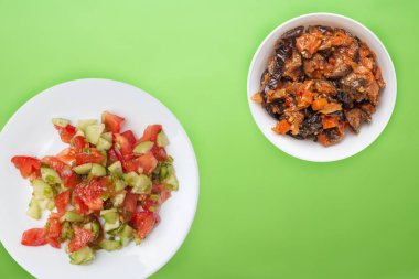 Salatalık, domates ve yeşil soğanlı vejetaryen salatası. Limonlu arka planda beyaz tabakta vejetaryen salatası. Sağlıklı sebze kahvaltısı.