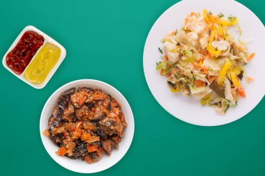 Beyaz tabakta sebze turşusu. Yeşil arka planda vejetaryen yemekleri. Kırsal yiyecekler. Düz yatıyordu.