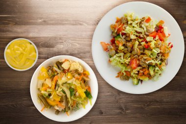 Tavuk mideli salata ile sebze havuç, soğan, biber, lahana, domates, brokoli. Kahverengi ahşap arka planda beyaz tabakta tavuklu salata.