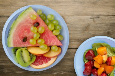 Kahverengi ahşap arka planda dilimlenmiş meyve. Açık mavi bir tabakta dilimlenmiş meyve manzarası