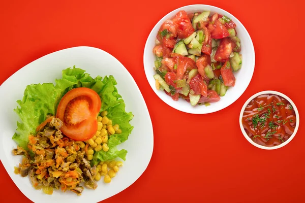 salad with chicken stomachs with carrots and corn and salad on a white plate. chicken salad with vegetables on a red background