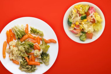  Beyaz tabakta Provencal sebzeler. Kırmızı arka planda kızarmış sebzeler. Vejetaryen yemeği. Sağlıklı yiyecek manzaralı.