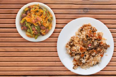 Kabaklı pilav, domatesli ve biberli beyaz tabakta. Turuncu ahşap arka planda sebzeli pirinç. Sağlıklı vejetaryen yemeği. Asya mutfağı üst görünümü