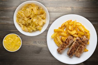 Beyaz tabakta domuz kaburgası ve patates, sebze salatası ve siyah ahşap arka planda sos. Fast food 'un en iyi manzarası. Sağlıksız yiyecekler.