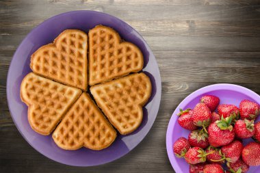 Siyah ahşap arka planda meyveli Belçika waffle 'ları. Mor bir tabakta waffle.