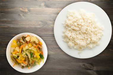 Beyaz tabakta beyaz pirinç. Siyah ahşap arka plan manzaralı sebze salatalı pirinç. Asya yemekleri.