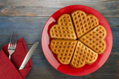Tahta zemin üzerinde çatal ve bıçak olan Belçika waffle 'ları. Kırmızı bir tabakta gözleme.