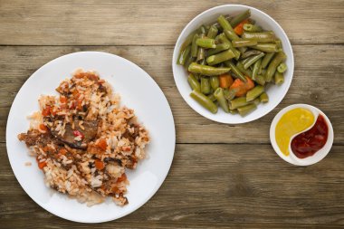 rice with braised zucchini with tomatoes and peppers on a white plate. rice with vegetables on wooden background. healthy vegetarian food. Asian cuisine top view