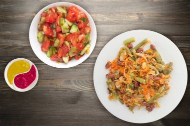  Vejetaryen salata manzarası. Sağlıklı yiyecekler. Fasulye salatası, kuşkonmaz, soğan, havuç ve susam siyah ahşap arka planda beyaz bir tabakta..