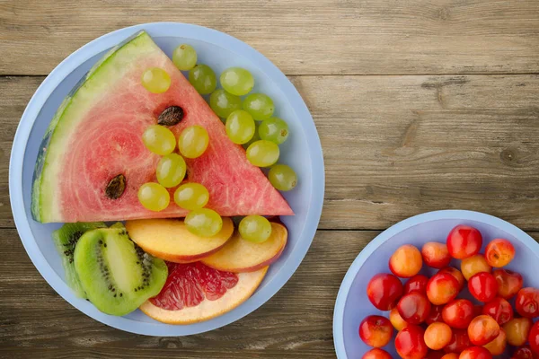 sliced fruit on a brown wooden background. sliced fruit on a light blue plate top view