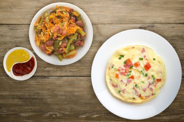 Beyaz bir tabakta domatesli ve yeşil soğanlı omlet. Tahta arka planda izole edilmiş. Sebze salatalı omlet. sağlıklı kahvaltı