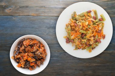 Vejetaryen salata manzarası. Sağlıklı yiyecekler. Fasulye salatası, kuşkonmaz, soğan, havuç ve susam mavi ahşap arka planda beyaz bir tabakta.