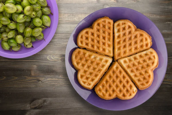Siyah ahşap arka planda meyveli Belçika waffle 'ları. Mor bir tabakta waffle.