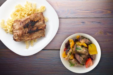 grilled pork ribs with pasta. grilled pork ribs on a white plate on  a purple wooden background. grilled pork ribs top view