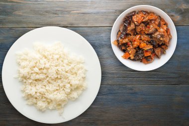 Beyaz tabakta beyaz pirinç. Mavi ahşap arka plan manzaralı sebze salatalı pirinç. Asya yemekleri.