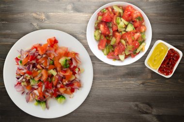 Vejetaryen yemeği. Biberli salata, domates, soğan, brokoli ve beyaz tabak. Siyah tahta arka planda vejetaryen salatası.