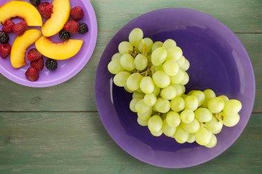 Yeşil ahşap arka planda üzümler. Mor plaka manzaralı üzümler. sağlıklı yiyecekler