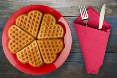 Tahta zemin üzerinde çatal ve bıçak olan Belçika waffle 'ları. Kırmızı bir tabakta gözleme.