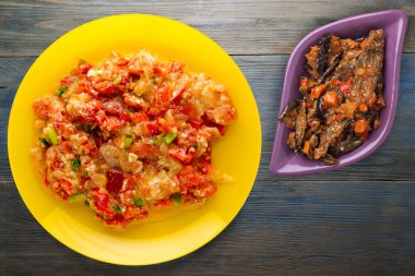 Mavi ahşap arka planda sarı tabakta soğanlı haşlanmış domates. vejetaryen yemeği