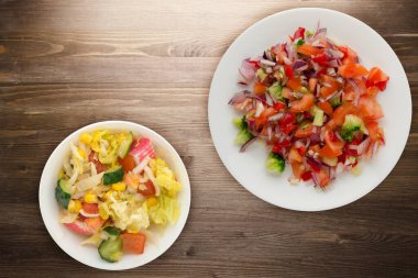 Vejetaryen yemeği. Biberli salata, domates, soğan, brokoli ve beyaz tabak. Kahverengi ahşap arka planda vejetaryen salatası