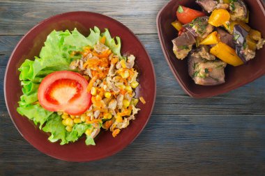 Tavuk mideli salata, havuç, mısır ve salata. Kahverengi tabak manzaralı. Mavi ahşap arka planda sebzeli tavuk salatası.