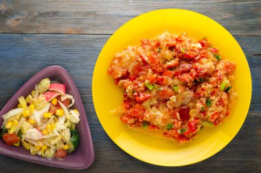 Mavi ahşap arka planda sarı tabakta soğanlı haşlanmış domates. vejetaryen yemeği