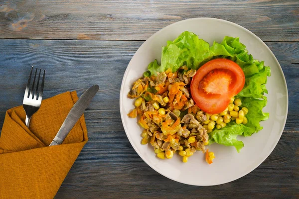 Salad with chicken stomachs with carrots and corn and salad on light gray plate with fork and knife top view. chicken salad with vegetables on blue wooden background — Stock Image Salad Chicken Stomachs Carrots Corn Salad Light Gray Plate Fork Stock Image