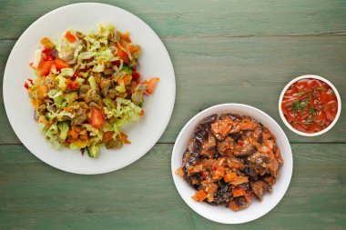 Tavuk mideli salata ile sebze havuç, soğan, biber, lahana, domates, brokoli. yeşil ahşap arka planda beyaz tabakta tavuklu salata