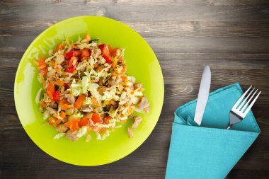  Tavuk mideli salata ile sebze havuç, soğan, biber, lahana, domates, brokoli. Limonlu tavuklu salata siyah ahşap arka planda çatal ve bıçak manzaralı.