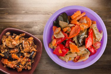 Kahverengi ahşap arka planda sebze güveci. Mor tabakta Bulgar güveci ve vejetaryen salata üstü manzarası