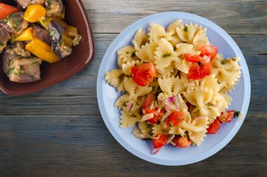 Vejetaryen salata manzaralı açık mavi tabakta makarna. makarnalar, domatesler, soğanlar, lahanalar mavi ahşap arka planda