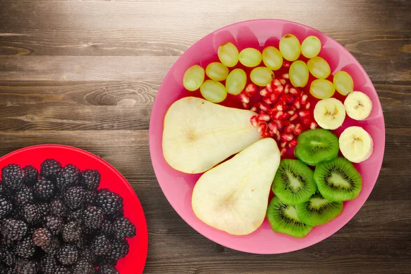 Fruktblandingspære Kiwi Druer Banan Granateple Brun Trebakgrunn Frukt Rosa Platetopp – stockfoto